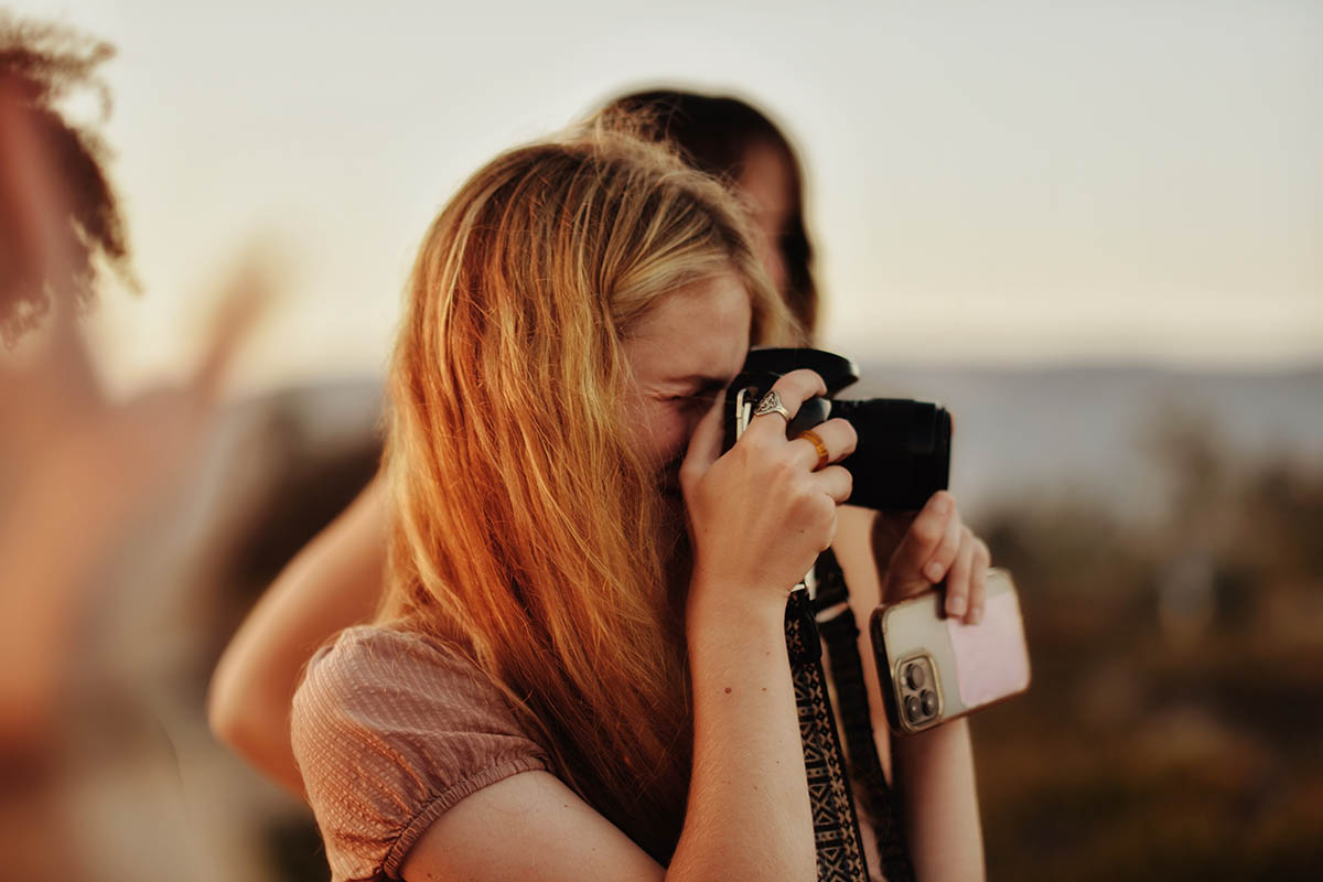 Person taking photo with camera outside at dusk.