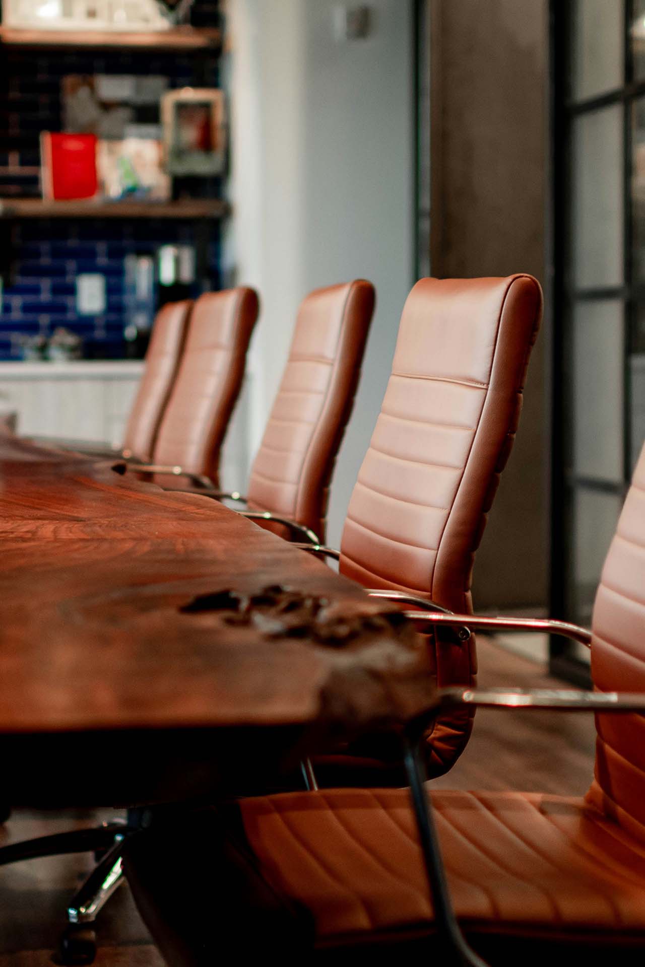Elegant office conference room with plush leather chairs and live edge wood table.