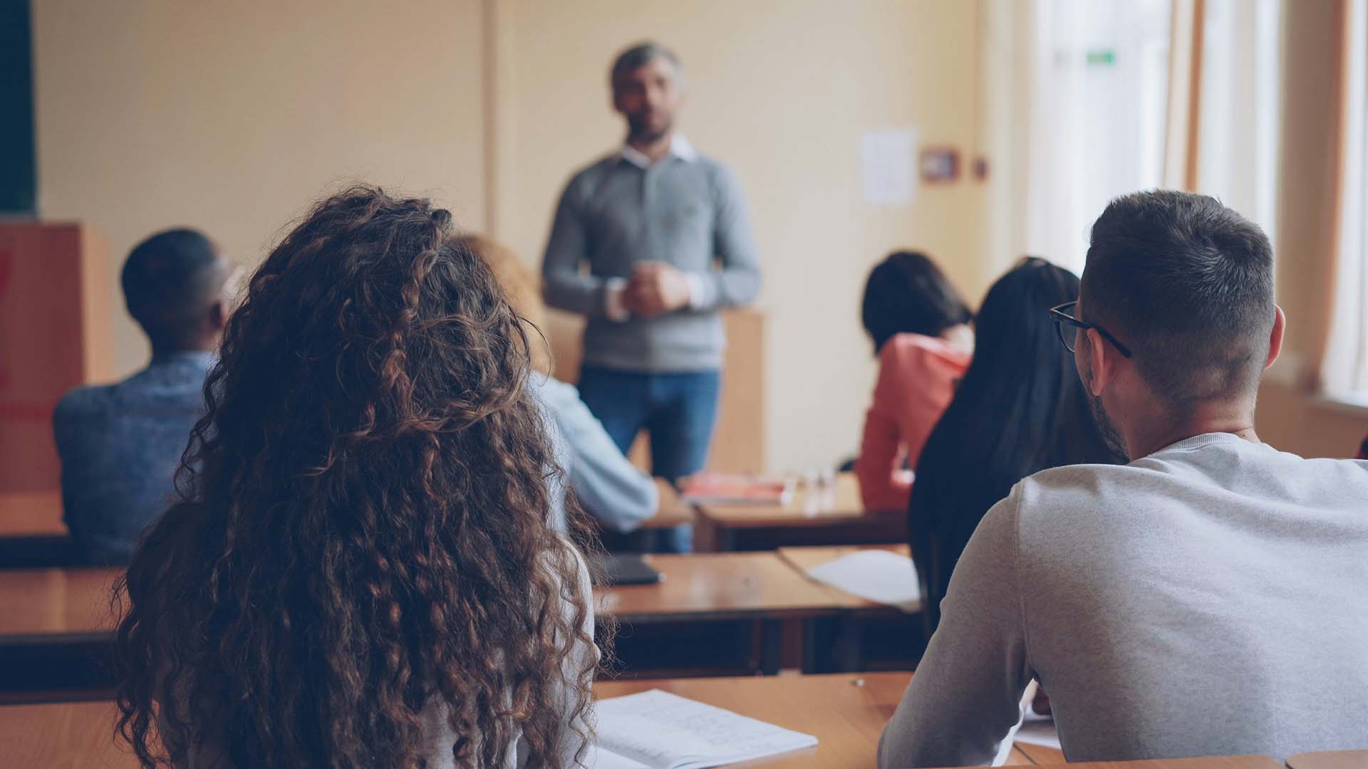 Photo of teacher in a collared shirt reviewing a lesson with his class.